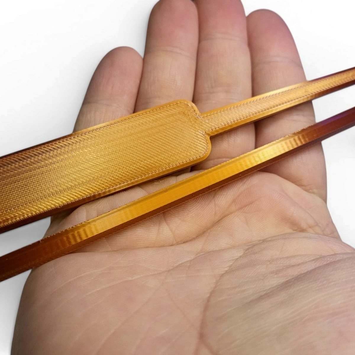 Copper-colored lockpick prop with textured handle held across an open hand for scale.