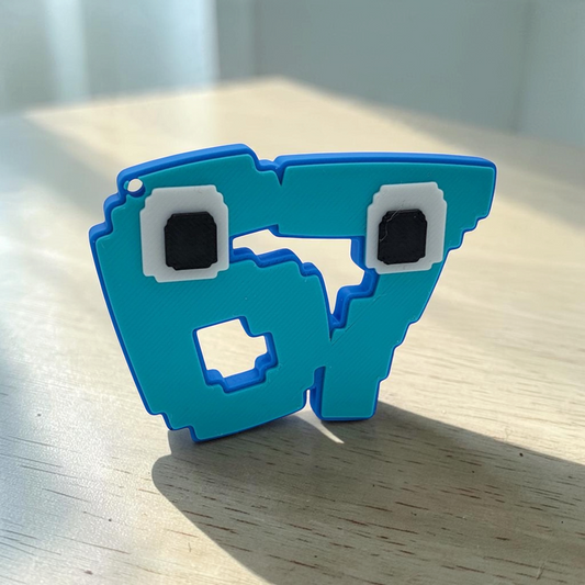 Front view of a blue pixelated 67 meme character keyring with square eyes on a white background.