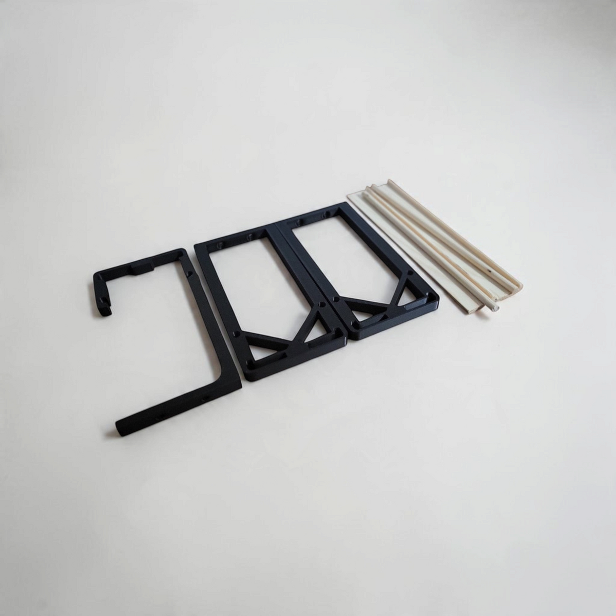 Black 3D printed end brackets and wooden dowels arranged as a DIY spice rack kit for cupboard storage.