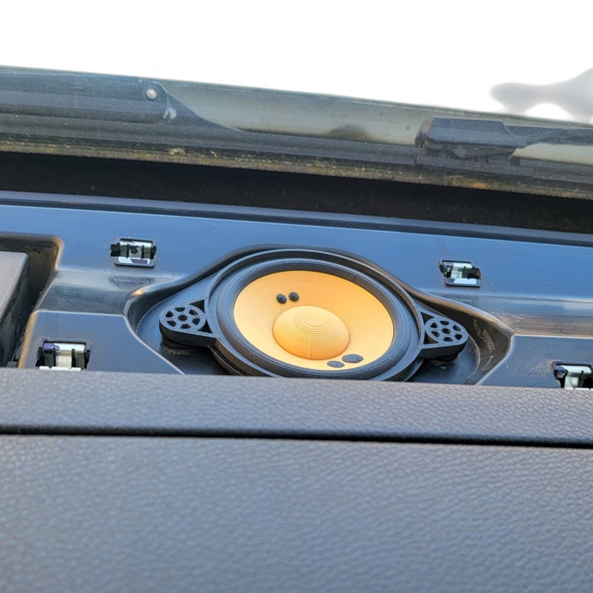 Yellow speaker-style storage insert fitted into a camper van dashboard compartment.