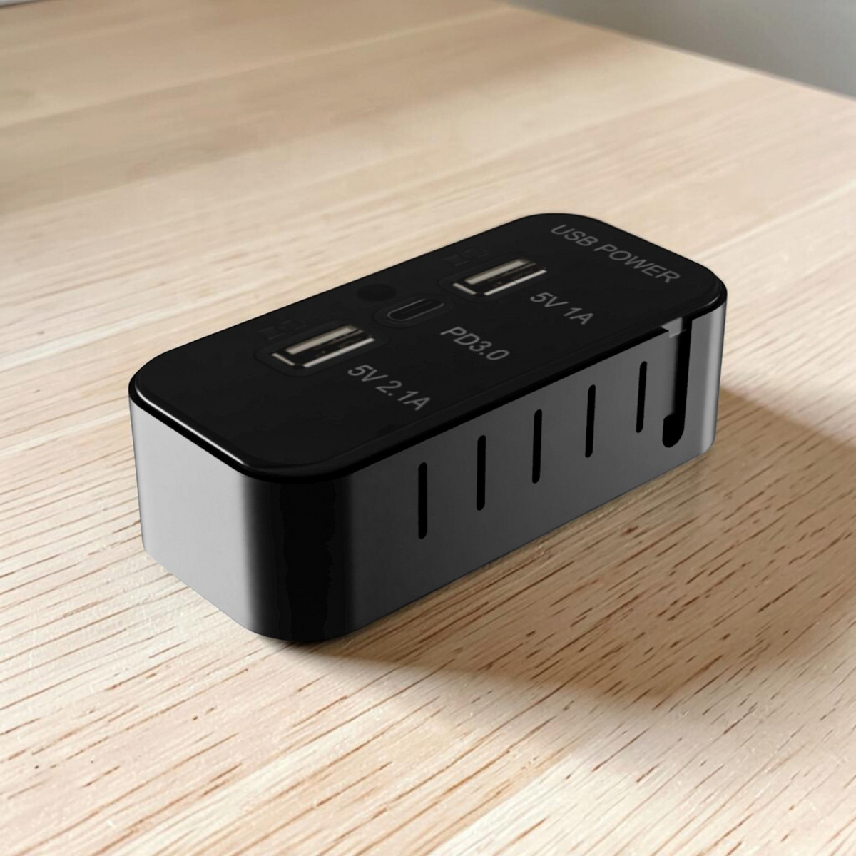 Black surface-mount case for a three-port 12V camper van USB outlet, shown on a wooden surface.
