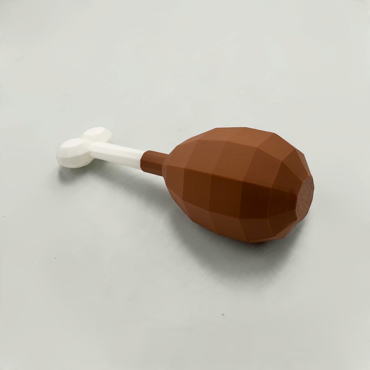 Angled view of a brown turkey leg cosmetic fan art with a white bone on a white background
