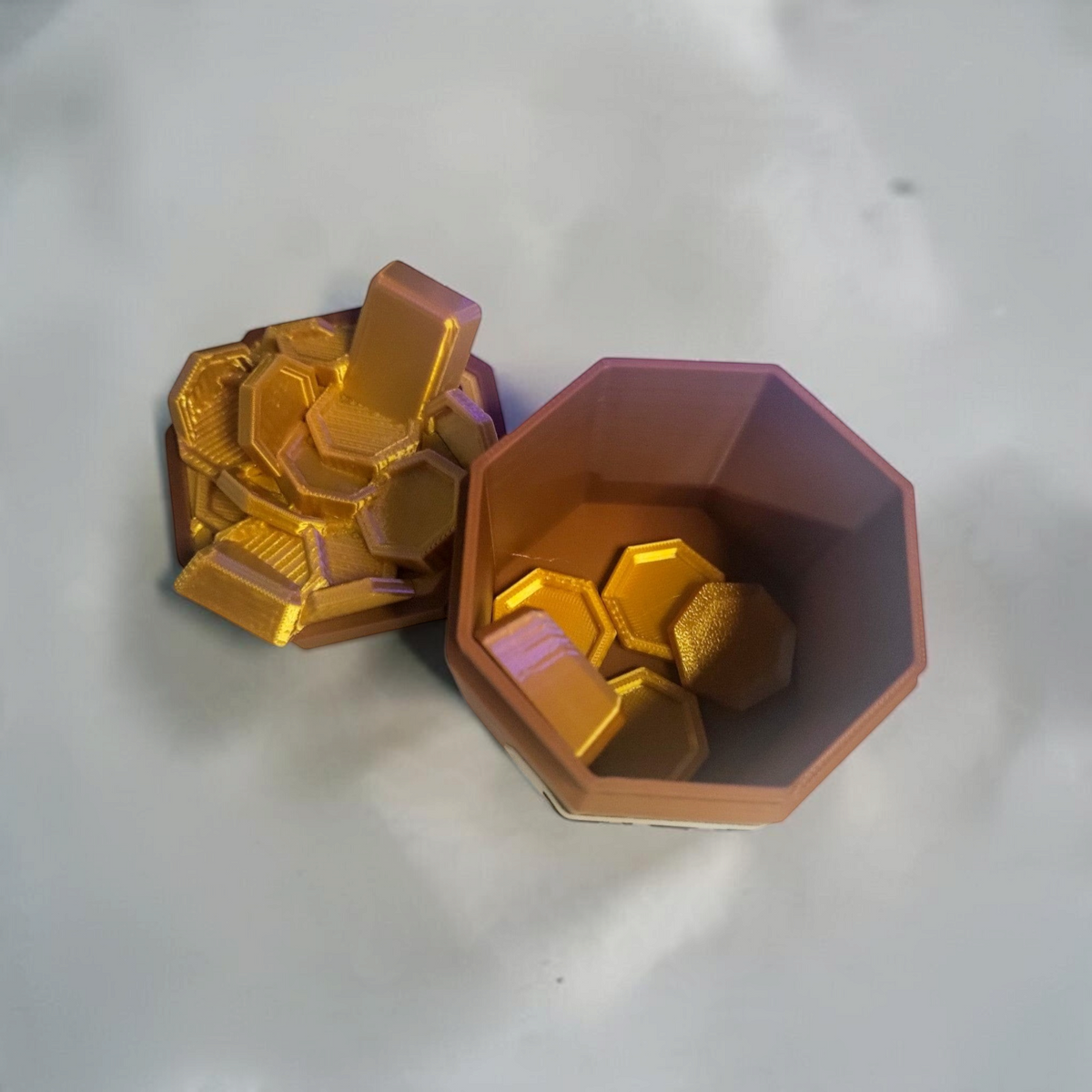Open hexagonal bone and copper tip jar displayed with gold coin and bar accents on a light surface.
