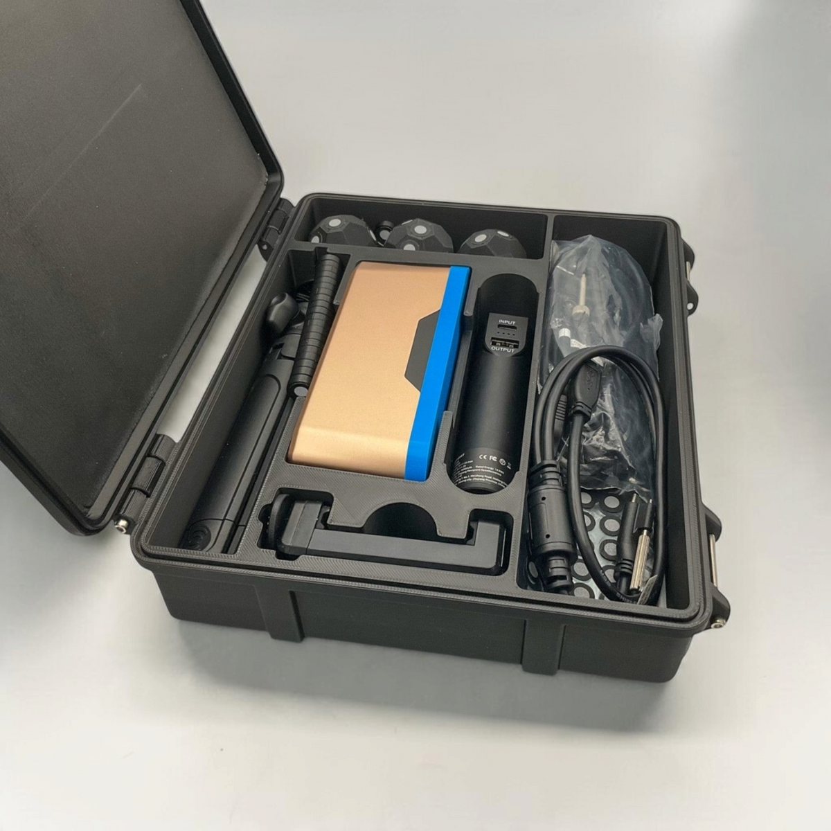 Open black scanner case with fitted foam slots for the scanner, cables and accessories.
