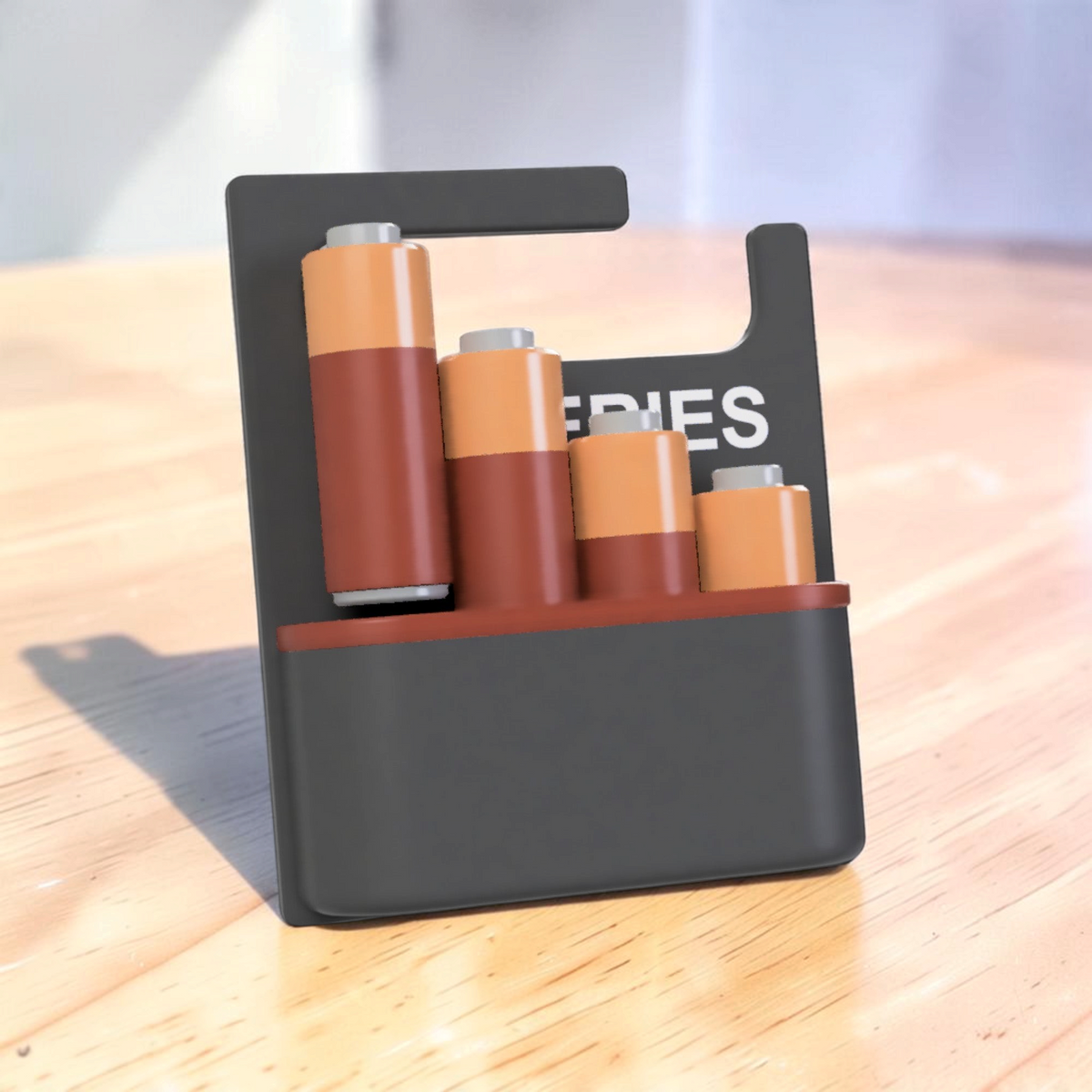 Black 3D-printed battery organiser with a front storage compartment, holding copper-coloured batteries of different heights.
