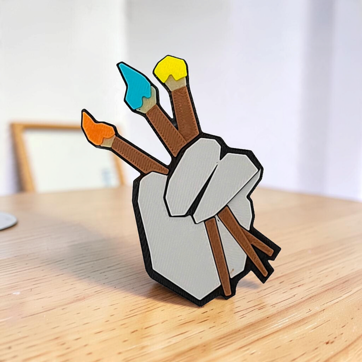 Close-up of the Gorilla Tag illustrator badge fan art with three colourful paintbrushes on a wooden table.